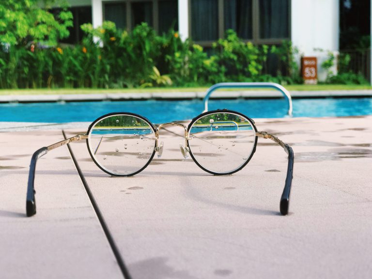Glasses on the floor next to an outdoor pool.