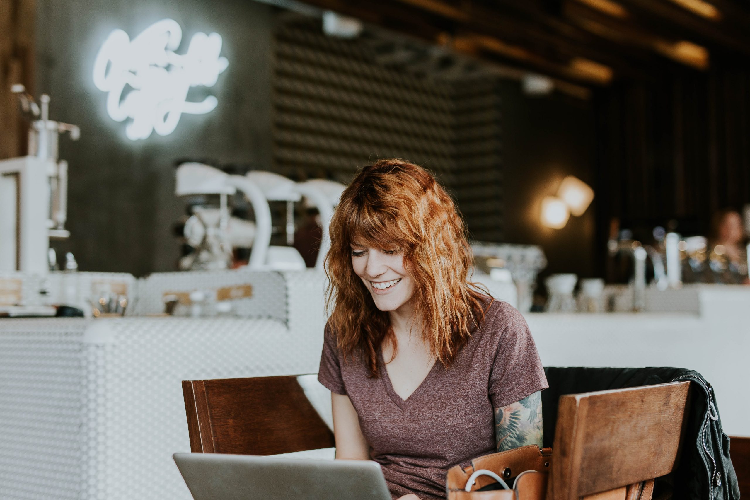 A girl looking and smiling at a laptop.