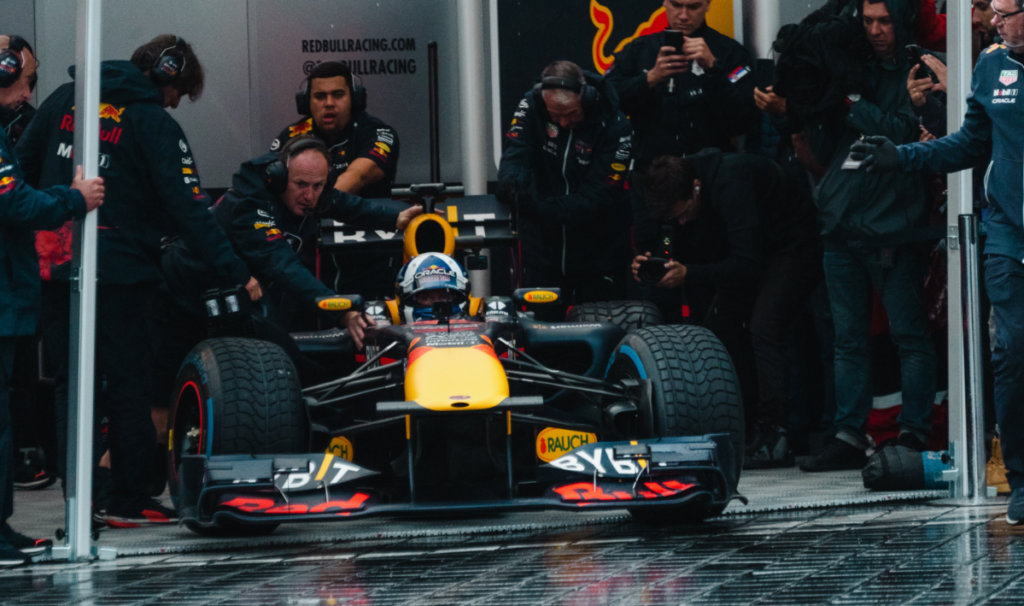 A Formula 1 racing team maneuvering a Formula 1 car out of a pit lane