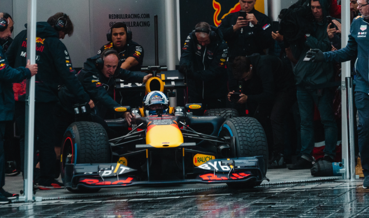 A Formula 1 racing team maneuvering a Formula 1 car out of a pit lane