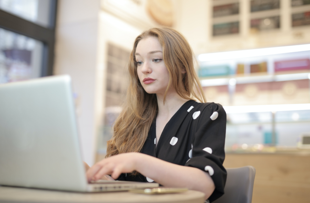A girl typing on a laptop, wearing a polk dot dress